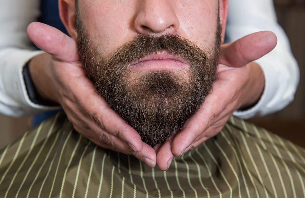 hombre cuidando su barba con el barbero en Revista YO CANCÚN, Quintana Roo.