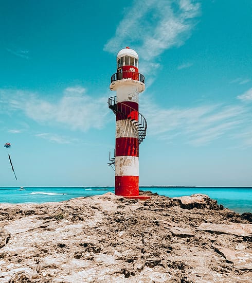 Fotografía panorámica del faro de punta cancún y el mar turquesa en una de las playas públicas de Cancún para la guía de la Revista YO CANCÚN, Quintana Roo.